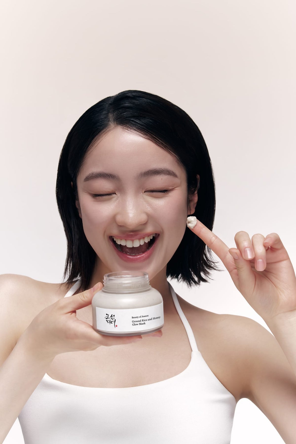 Woman holding a skincare product with a plain background
